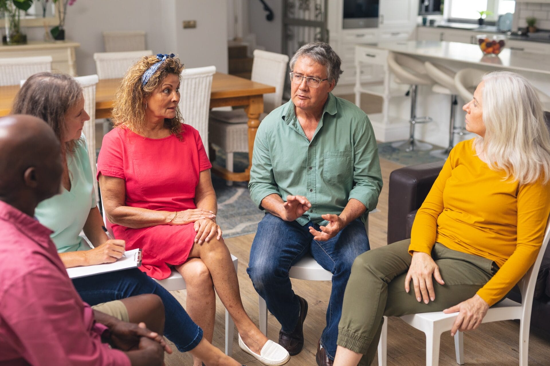 Багаторасові старші чоловіки та жінки обговорюють під час сесії групової терапії