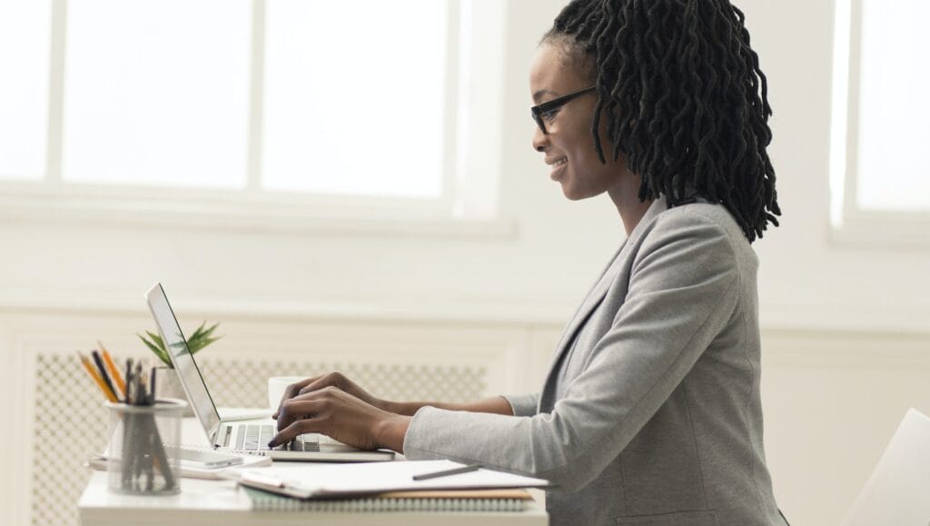 Афро-американських леді за допомогою ноутбука в офісі, вид збоку, панорама