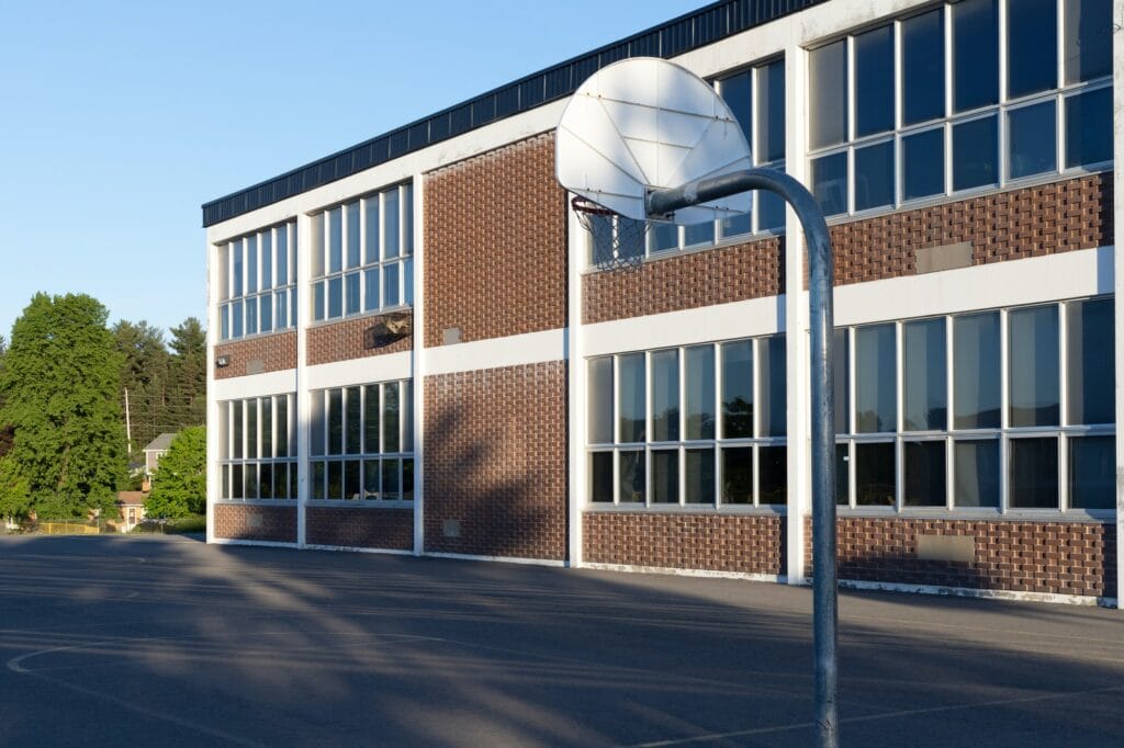 Будівля школи та шкільне подвір'я з баскетбольним майданчиком