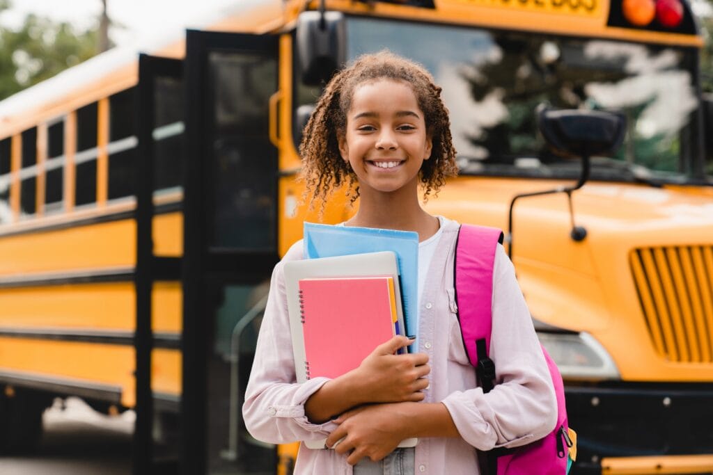 Усміхнена афро-американська школярка повертається до школи з книгами та зошитами